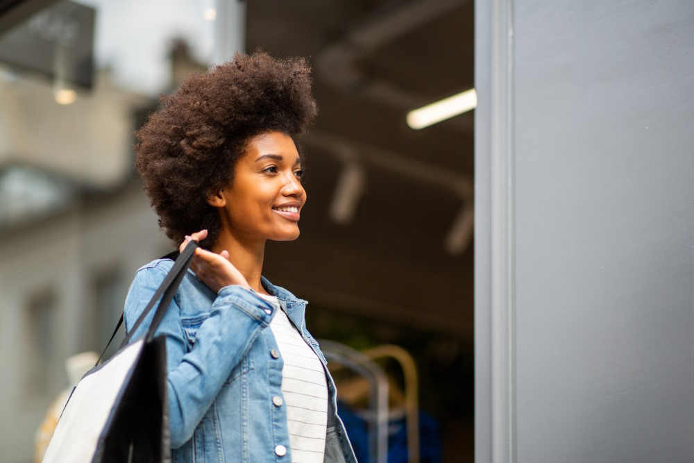 african american woman window shopping for clothes by store